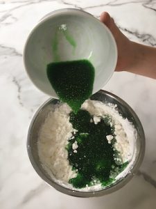 POURING GREEN FOOD COLOURING INTO CORNFLOUR