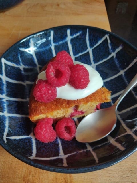 Raspberry Pud with fresh raspberries and cream on a blue ceramic bowl
 