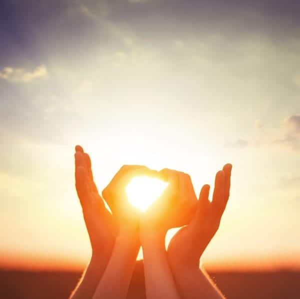 hands catching the sunset with light shining through