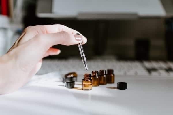 essential oil dropper in hand with little bottles displayed