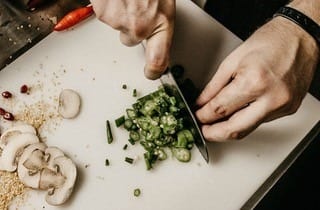 masculin hands chopping green veggies on a chopping board