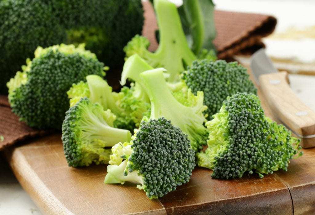 cut broccoli on a wooden board with a knife