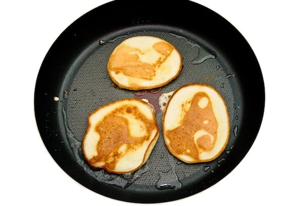 Fritters on a frying pan pancakes on the griddle on the white isolated background