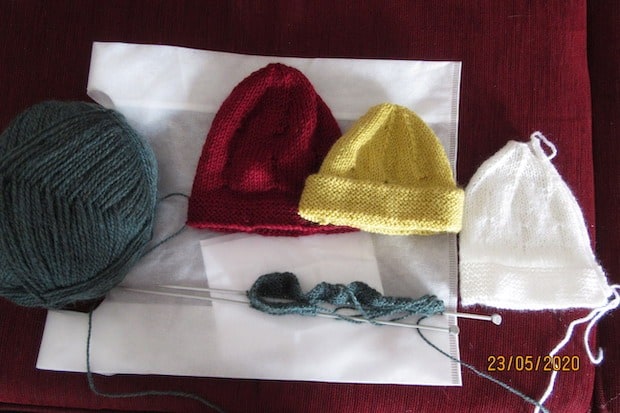 baby beanies with ball of wool and knitting