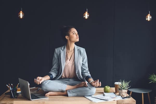 lady sitting on a busy office desk doing a mantra for alleviating stress