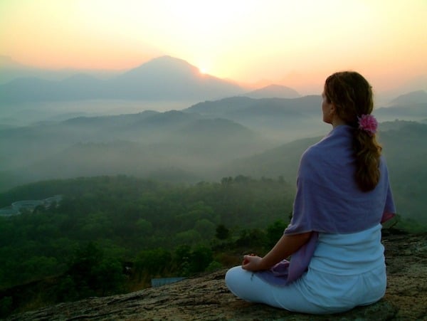 girl meditating on a hill top at sunrise in the mountains
