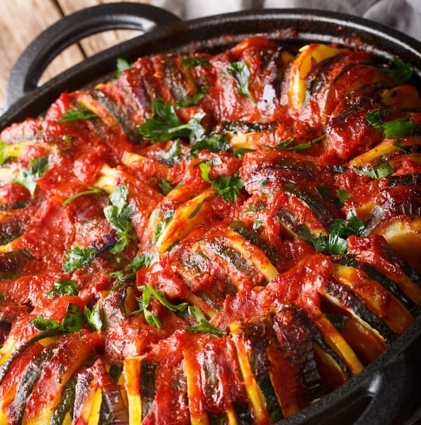 Greek cuisine Briam vegetable mix close-up in a pan on the table. vertical