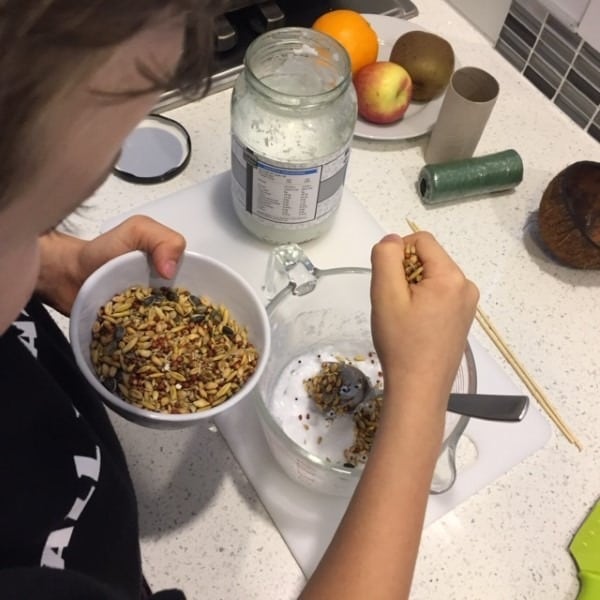 Eli sprinkling seeds onto the coconut oil for bird food