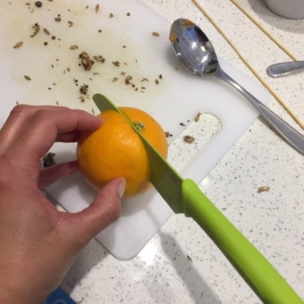 slicing a chunk out of an orange to scoop out the inside