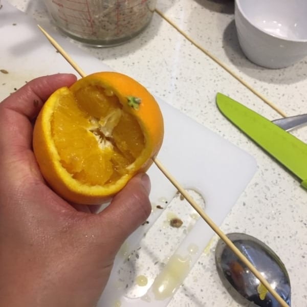 piercing an orange with a skewer