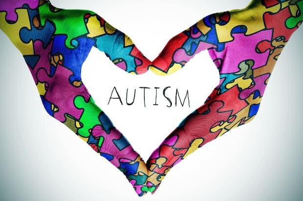 text autism and hands forming a heart with puzzle pieces